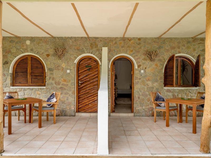 Terrace with stone wall, wooden doors, and outdoor tables with chairs.