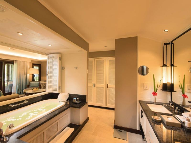 Área de baño moderna en hotel con bañera, doble lavabo y decoración elegante.