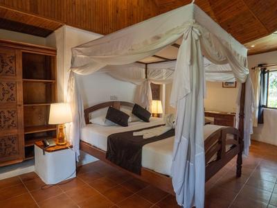 Elegantes Schlafzimmer mit Himmelbett, Holzmöbeln und warmem Holzdeckenakzent.