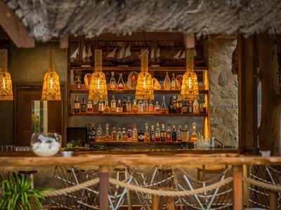 Przytulny bar z drewnianym kontuarem, słomianymi stołkami i ciepłym oświetleniem w tropikalnym otoczeniu