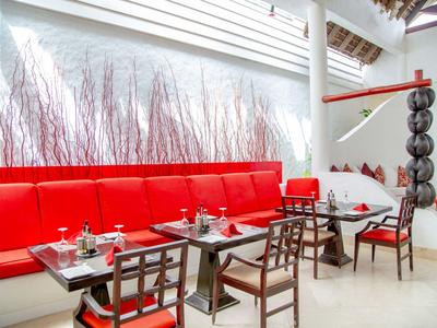 Modernes Restaurant mit roten Sitzbänken, schwarzen Stühlen und hellen Wänden