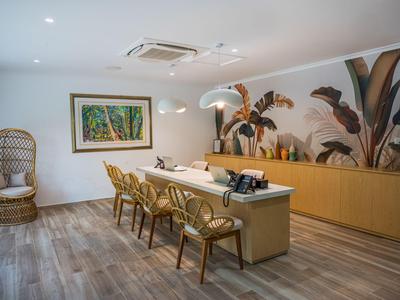 Area reception moderna con ampio pavimento in legno, scrivania e piante decorative sulla parete.