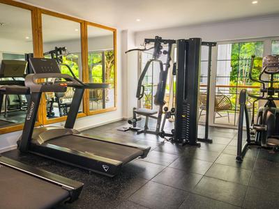 Palestra con tapis roulant e attrezzi ginnici in un ambiente alberghiero luminoso.