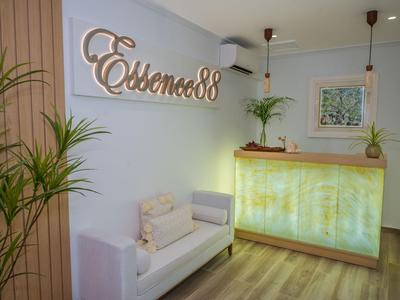 Area reception moderna con bancone illuminato e divano bianco in stanza luminosa.