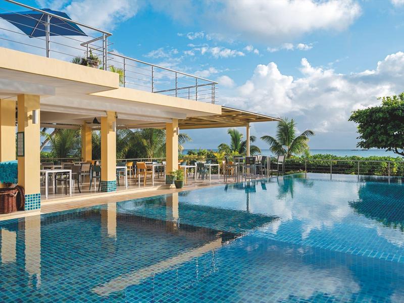 Modern zwembadgebied met overdekte zitplaatsen en uitzicht op zee.