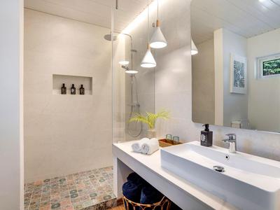 Modernes Badezimmer mit großer Dusche, Waschbecken und stilvoller Beleuchtung.