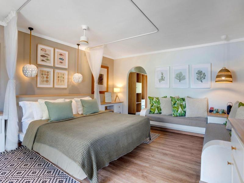 Jasny pokój hotelowy z podwójnym łóżkiem, drewnianą podłogą i nowoczesnym wystrojem.