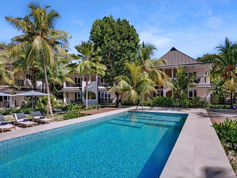 Nowoczesny basen z leżakami i palmami przy tropikalnym hotelu.