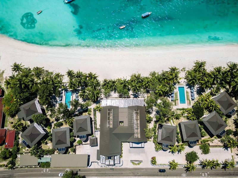 Widok z lotu ptaka na kompleks hotelowy przy plaży z basenami i palmami.