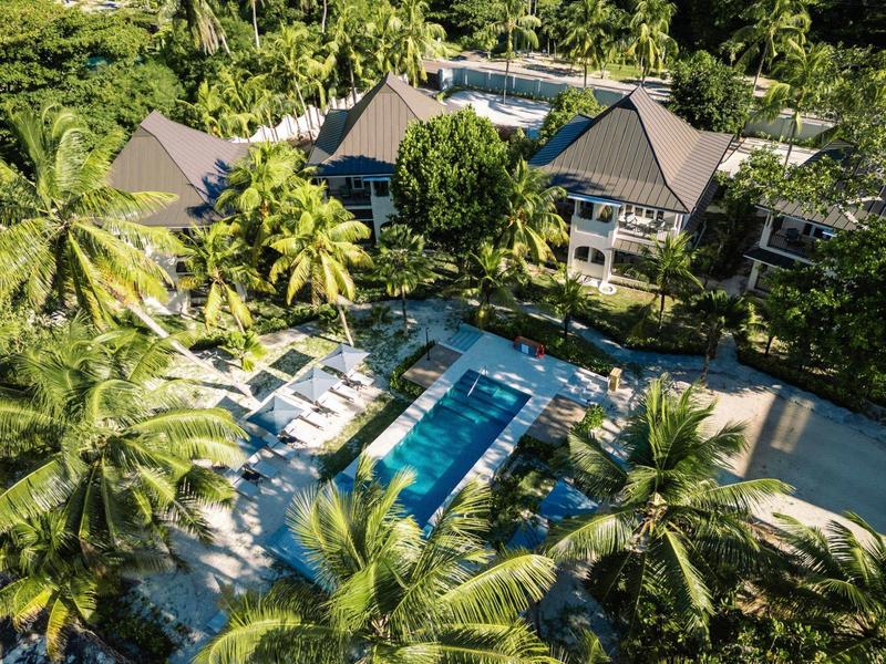 Luksusowa willa z basenem, otoczona bujną zielenią i palmami, idealna na relaksujące wakacje.