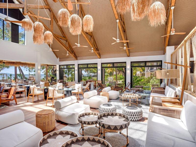 Jasny, nowoczesny salon hotelowy z dużymi oknami i wygodnymi miejscami do siedzenia.