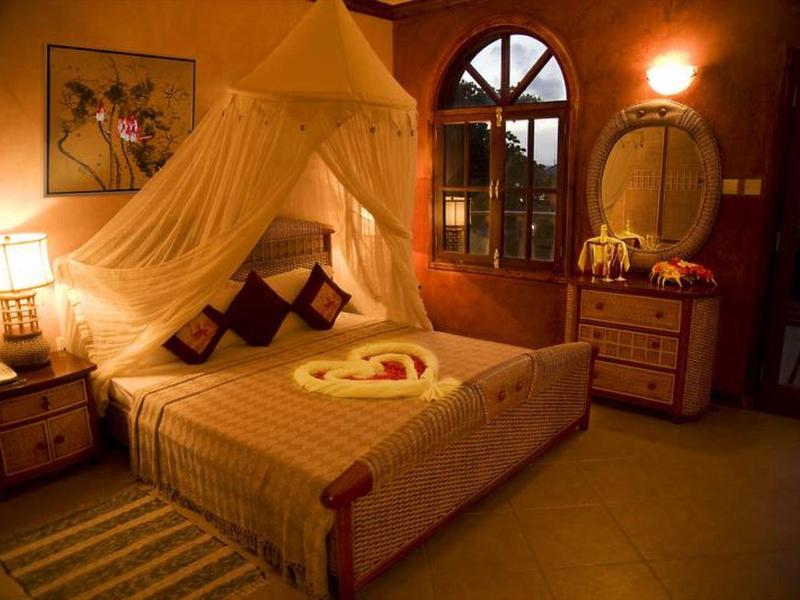 Gemütliches Schlafzimmer mit Holzmöbeln, Himmelbett, warmem Licht und dekorativem Netz.