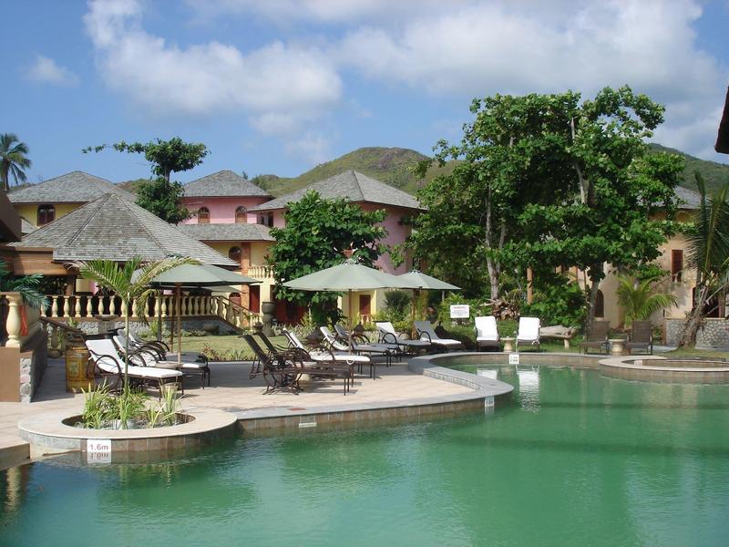 Einladender Poolbereich mit Liegestühlen, Sonnenschirmen und umgeben von Gebäuden und Bäumen.