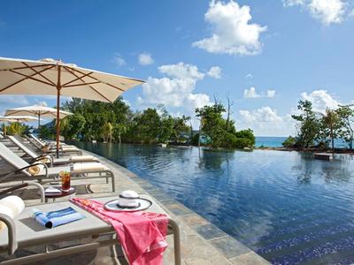 Infinity pool with loungers and umbrellas under blue sky and clouds