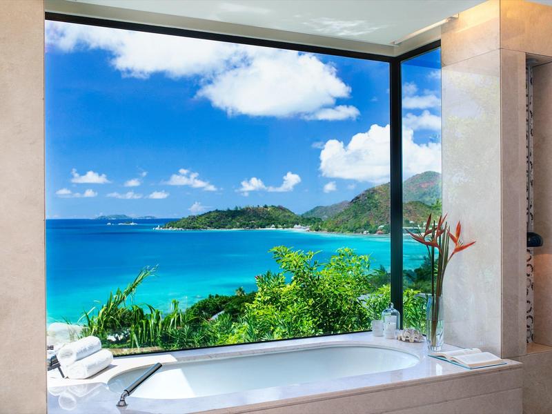 Lujosa bañera con ventana panorámica y vista al mar azul y a islas verdes.