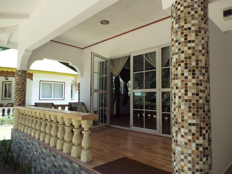 Veranda mit gemusterten Säulen, Glas-Schiebetür und Geländer aus Sandstein.