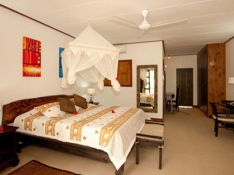 Przestronny pokój hotelowy z łóżkiem podwójnym, moskitierą, biurkiem i dekoracyjną sztuką ścienną.