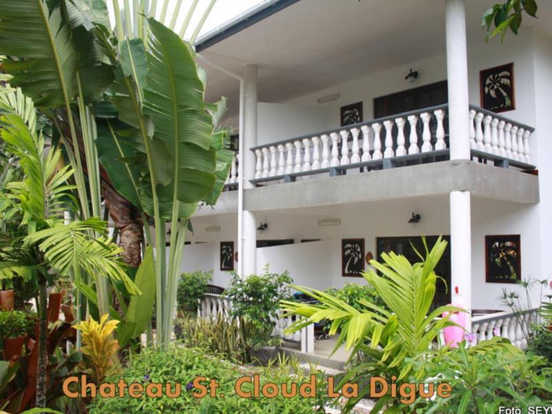 Dwupiętrowy hotel z balkonami i bujną tropikalną roślinnością