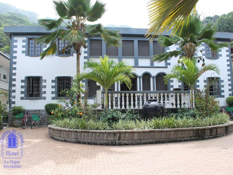 Dwupiętrowy budynek hotelu z okrągłą rabatą i tropikalnymi palmami z przodu