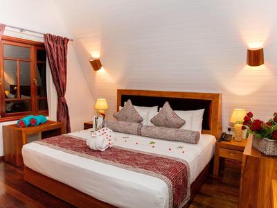 Gemütliches Hotelzimmer mit Doppelbett, Holzmöbeln und dekorativen Kissen.