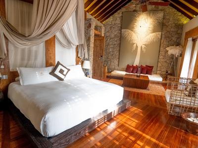 Elegant hotel room with wooden floors, a large bed, and cozy seating areas.
