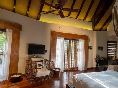 Elegant hotel room with wooden floors, exposed ceiling beams, and balcony access with daylight.