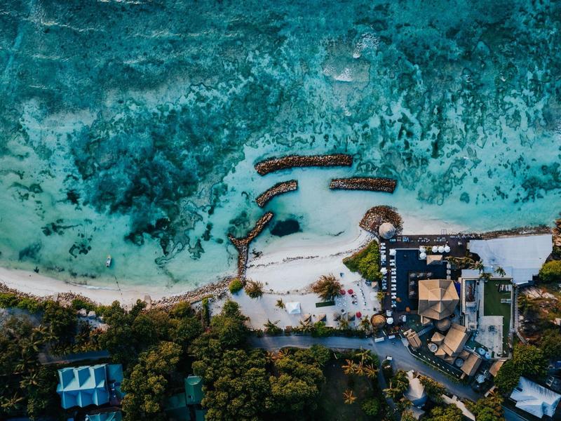 Aerial view of a resort with overwater bungalows on a white sandy beach.