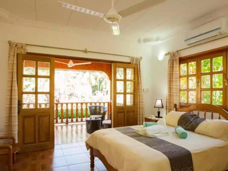 Helles Schlafzimmer mit Doppelbett, Holzmöbeln, großen Fenstern und Balkon mit Aussicht.