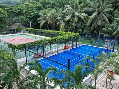Outdoor tennis and padel courts surrounded by tropical vegetation and palm trees.