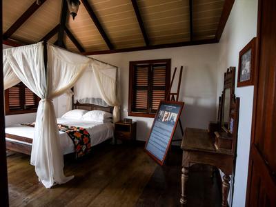 Cozy hotel room with canopy bed, wooden floor, and rustic furniture.