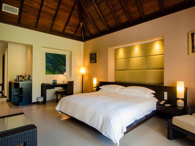 Habitación de hotel moderna con cama grande, escritorio, obras de arte y luz cálida.