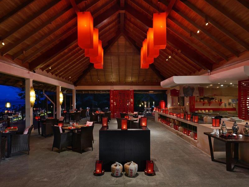 Offenes Restaurant mit Holzdach, moderner Beleuchtung und elegant gedeckten Tischen bei Nacht