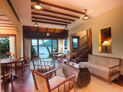 Helles Wohnzimmer mit Holzmöbeln, offener Küche, Deckenbalken und Blick auf einen Teich draußen.