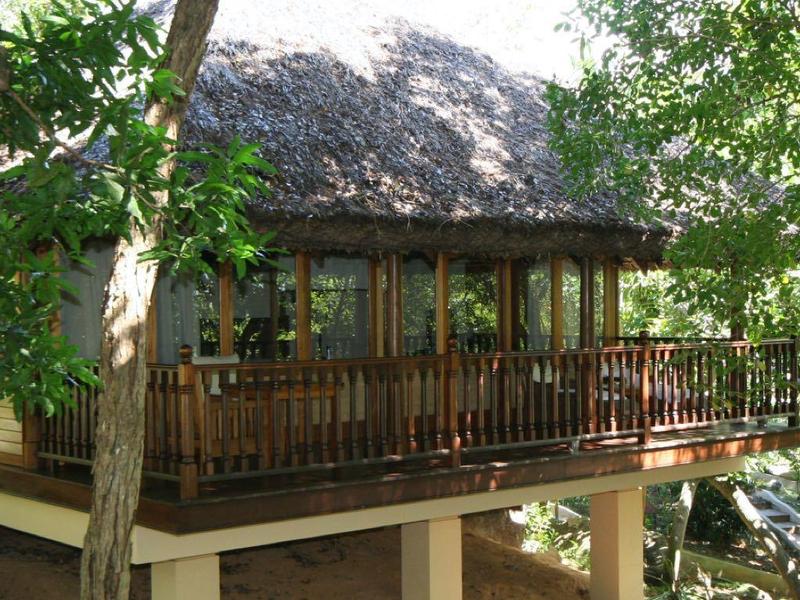 Treehouse with furnished terrace for relaxation, surrounded by green trees.
