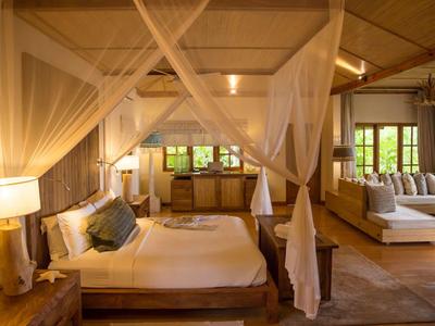 Gemütliches Hotelzimmer mit Himmelbett, Holzdecke und Sitzbereich in warmem Licht.