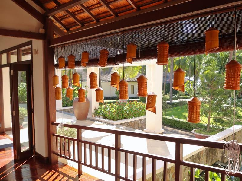 Traditionelle Terrasse mit Holzgeländer, orange Laternen und Blick auf grünen Garten mit Teich.