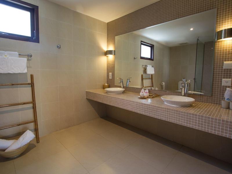 Modernes Badezimmer mit großer Spiegelwand, zwei Waschbecken und hellen Wandfliesen.