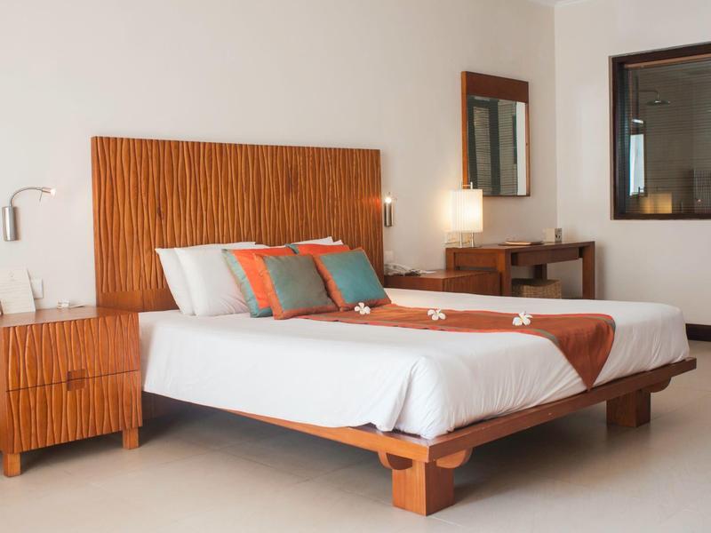 Modernes Schlafzimmer mit Doppelbett, hölzernem Kopfteil, Nachttisch und Schreibtisch.