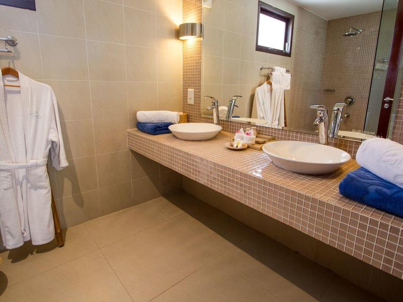 Modernes Badezimmer mit zwei Waschbecken, großen Spiegeln, Handtüchern und Bademänteln an der Wand.