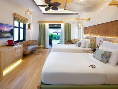 Světý hotelový pokoj s dvěma velkými postelemi, dřevěnou podlahou a přístupem do zahrady.