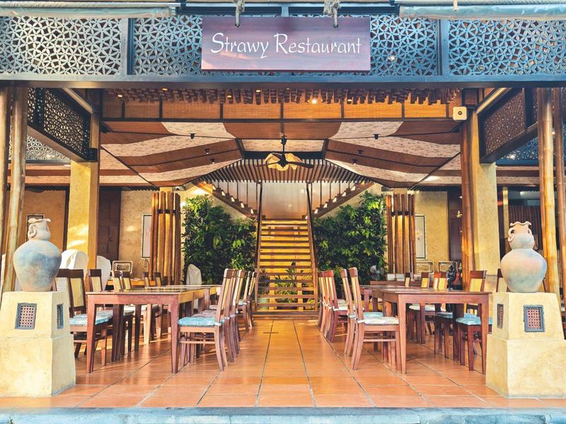 Elegantní otevřená restaurace s dřevěnými stoly, židlemi a centrálním schodištěm v pozadí