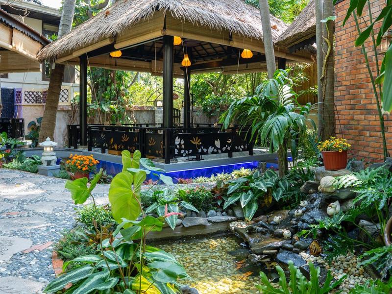 Tropická zahrada s altánem, posezením a malou jezírkem s rostlinami.