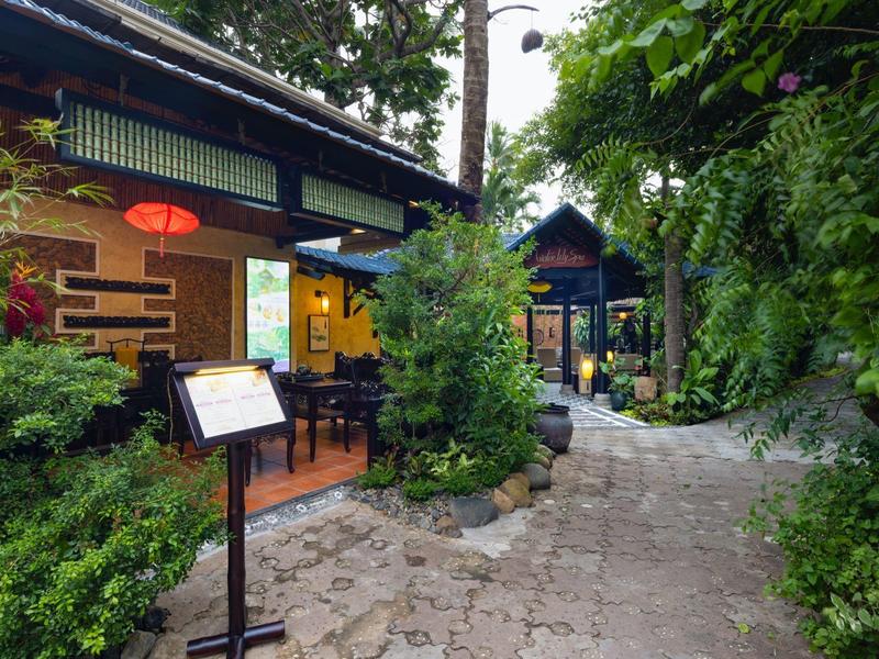 Příjemná zahradní cesta s tradičními budovami a bohatou zelení v hotelu.