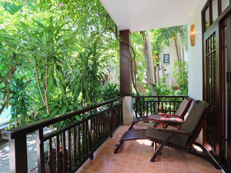 Balkon s dvěma lehátky a bujnou zelení v tropickém prostředí.