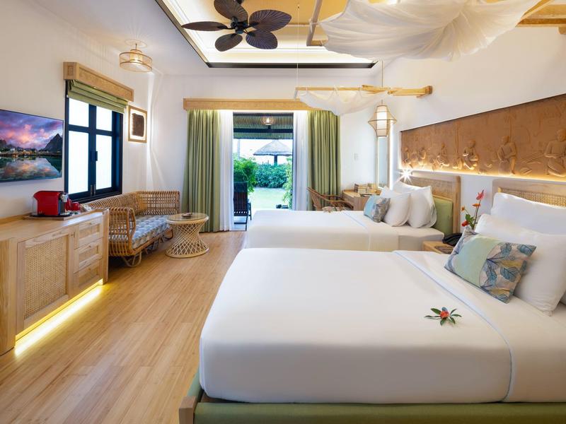 Světý hotelový pokoj s dvěma velkými postelemi, dřevěnou podlahou a přístupem do zahrady.