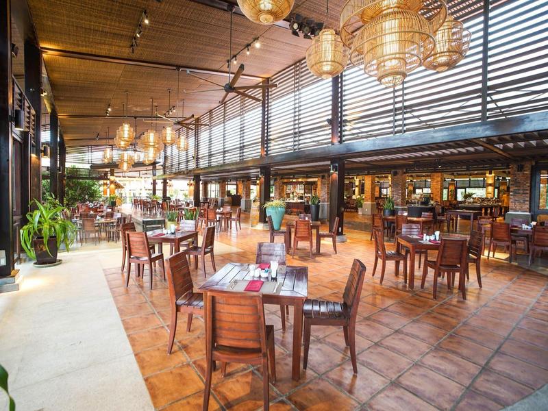 Ruim restaurant met houten tafels, stoelen en warme verlichting in een elegante sfeer.