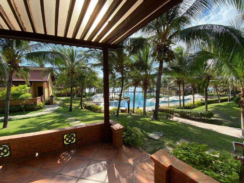 Overdekt terras met uitzicht op tropische tuin en zwembad in een hotelresort