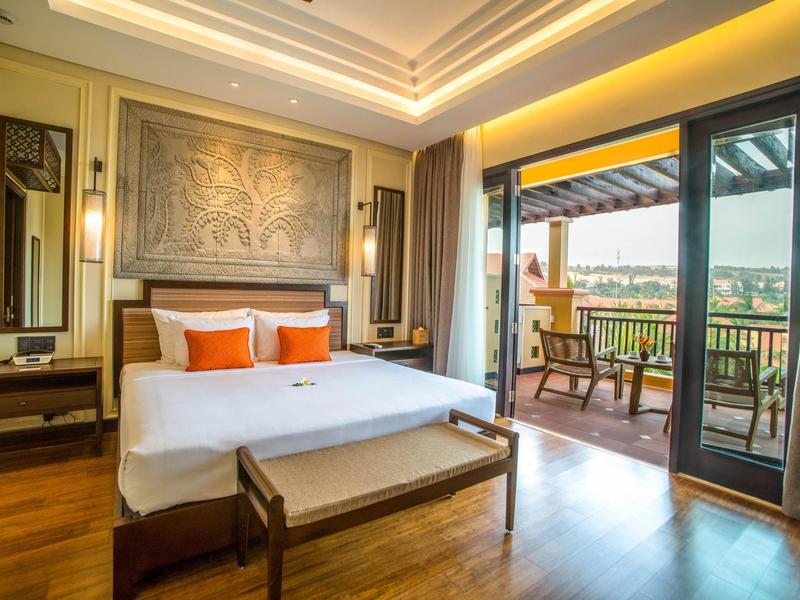 Elegant hotelkamer met groot bed, balkon en uitzicht op groen landschap.