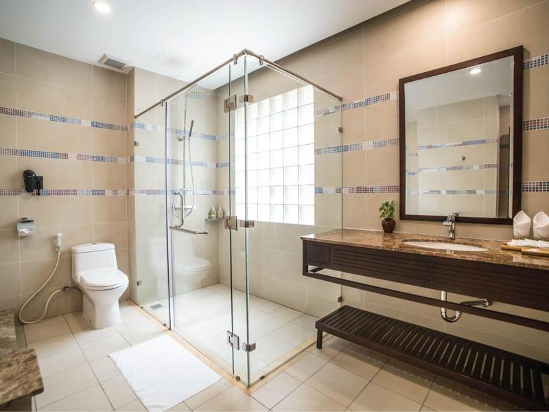 Lichte badkamer met glazen douche, toilet en brede wastafel met grote spiegel.