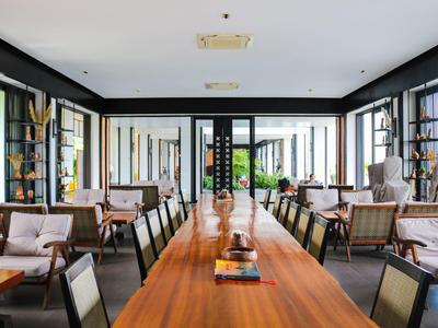 Jasna jadalnia z długim drewnianym stołem, miejscami do siedzenia, nowoczesnym wystrojem i dużymi oknami.